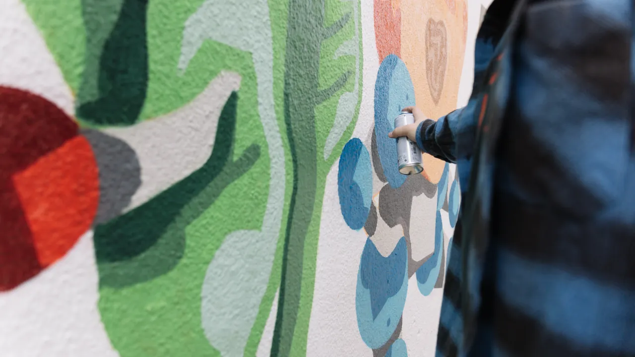 Artist painting a mural with spray paint